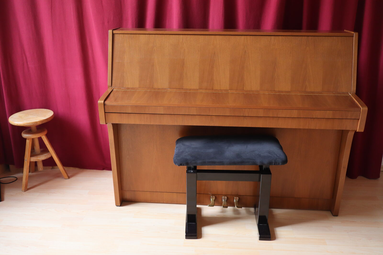 Übungsraum mit Klavier vor rotem Vorhang